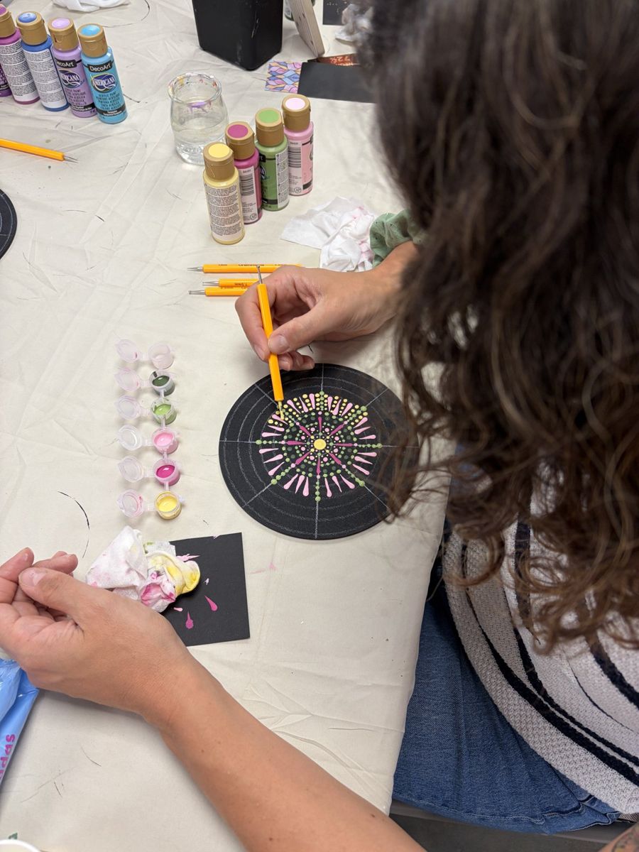 Alumna pintando un mandala de puntos rosa y verde en un taller