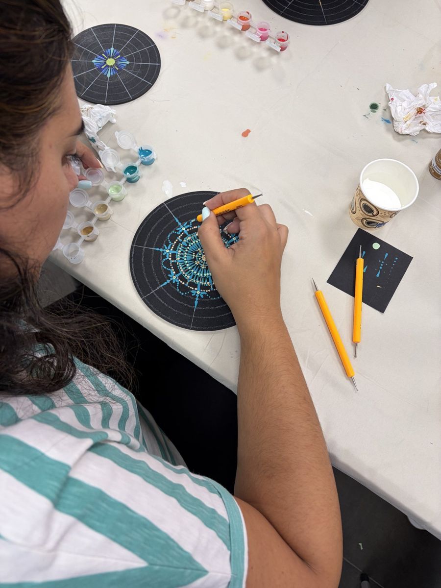 Alumna pintando un mandala de puntos azul en un taller